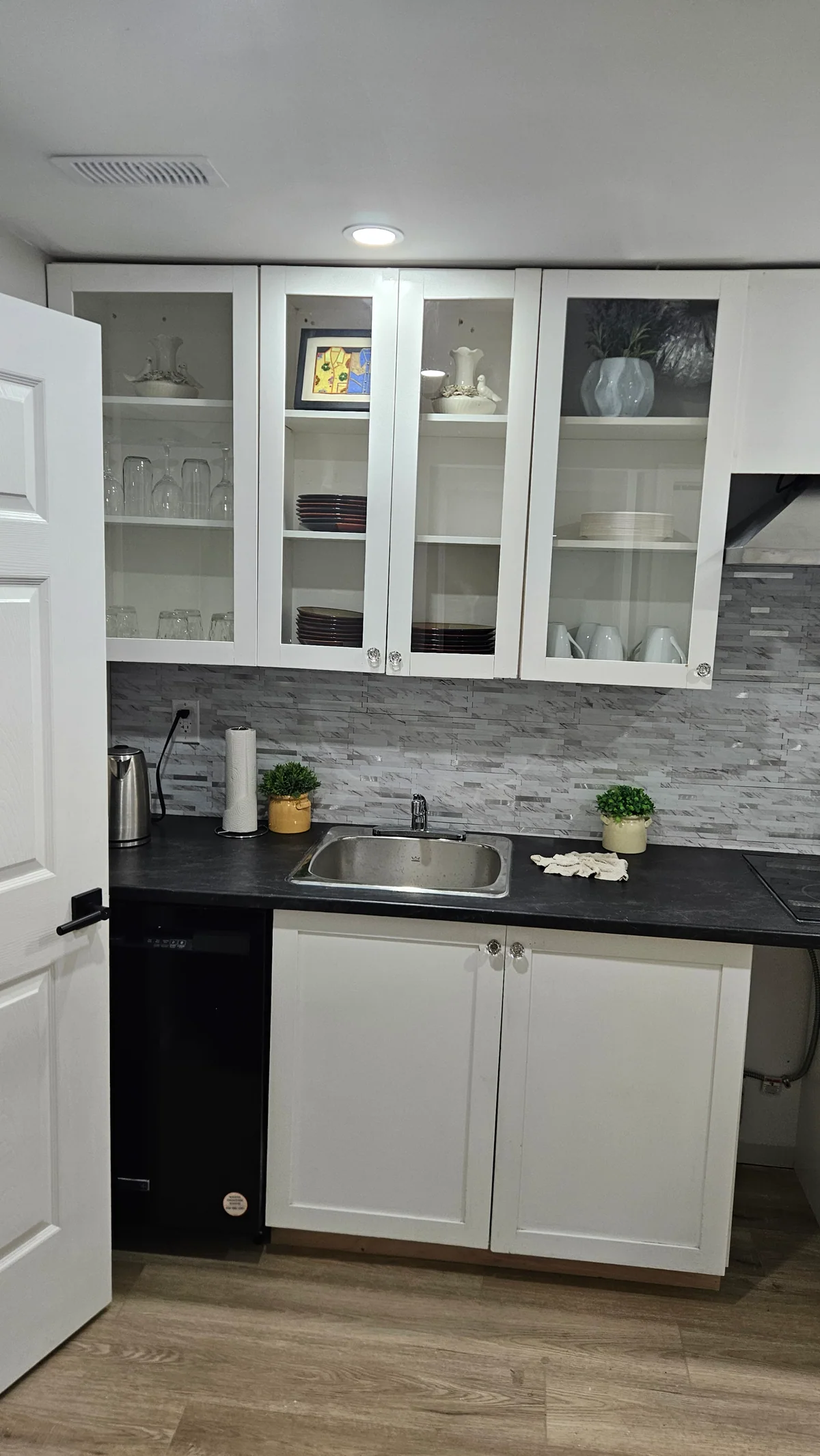 White glass-front cabinets above a finished basement wet bar