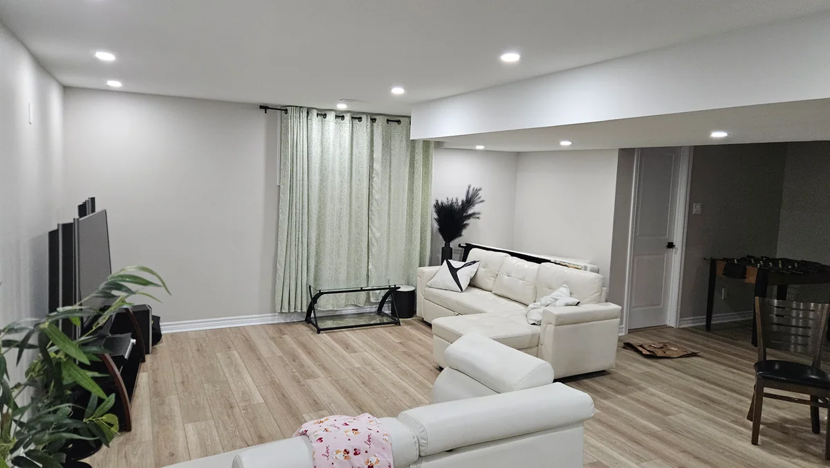 Open-plan finished basement lounge and dining area with recessed lighting