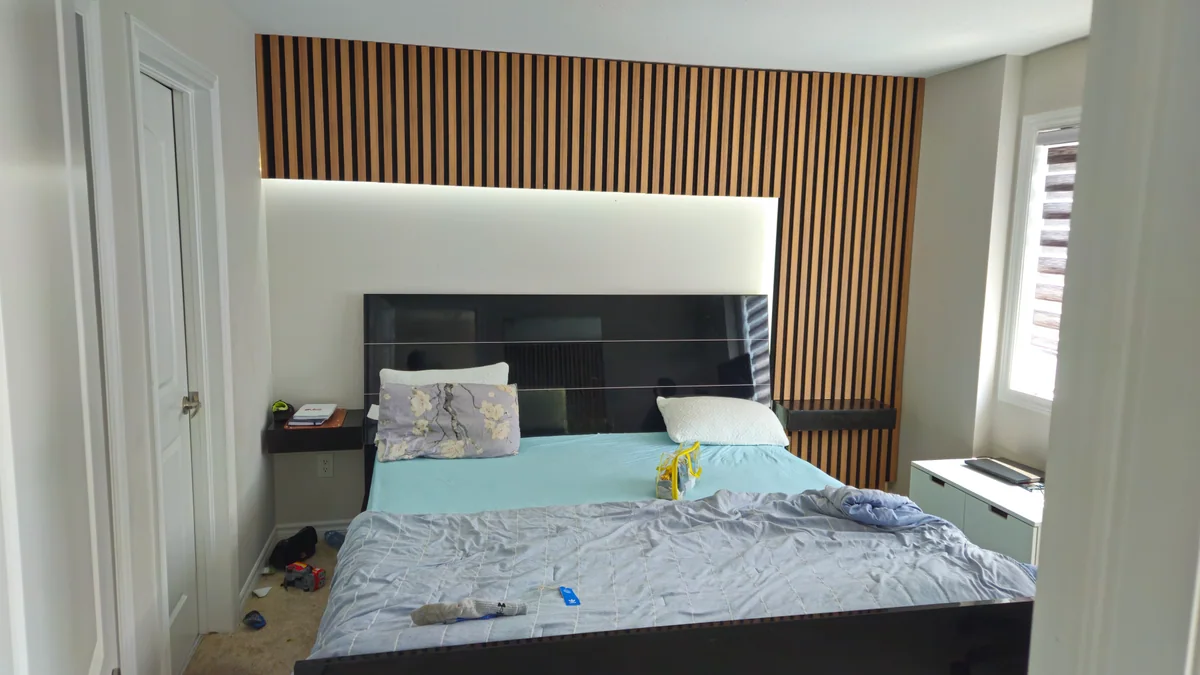 Bedroom headboard feature wall with vertical wood slats and concealed lighting
