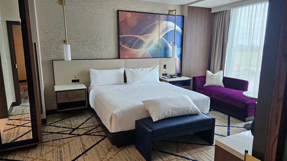 Contemporary hotel bedroom fit-out with upholstered bed and purple chaise