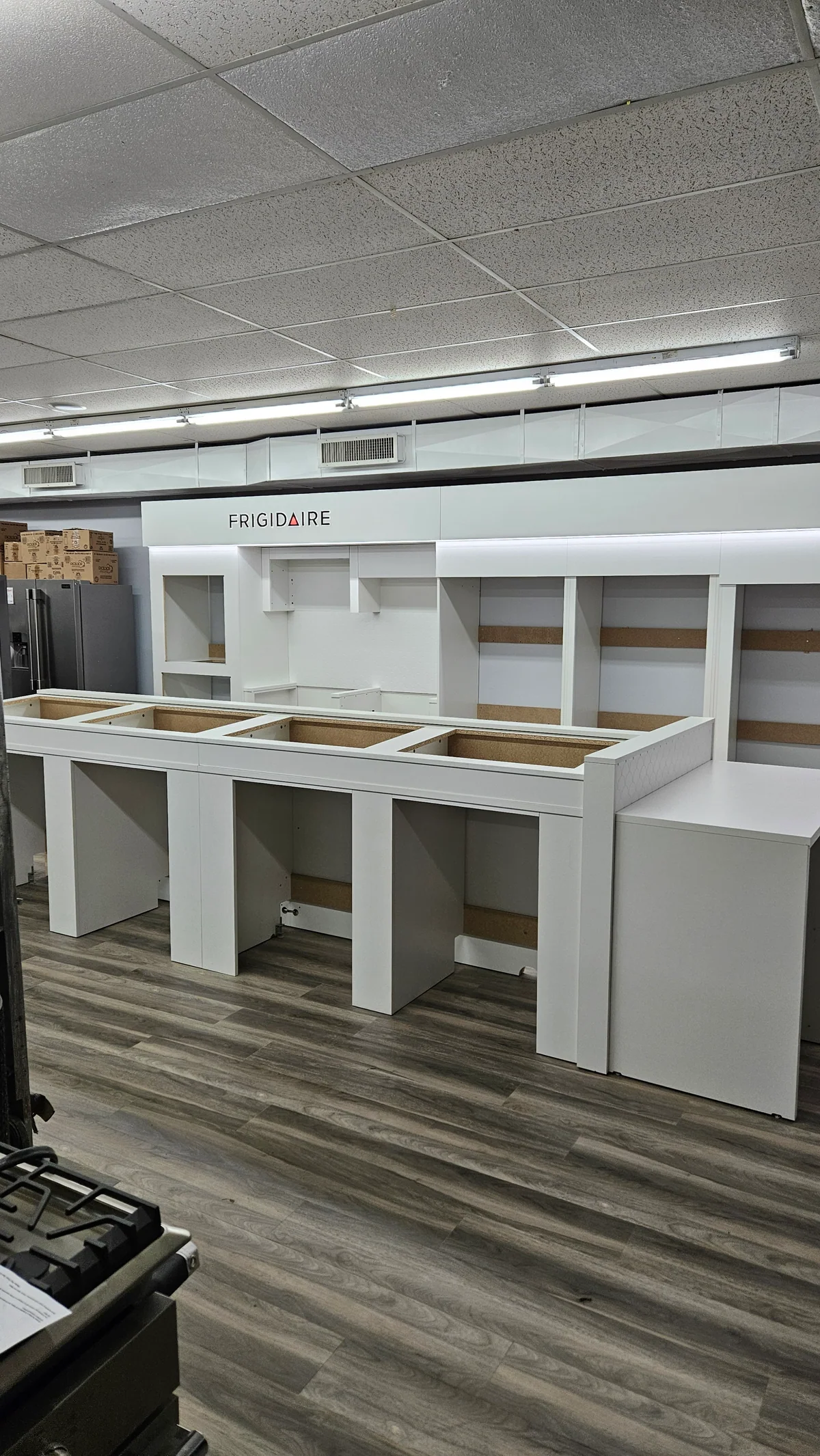 White appliance display cabinetry with open shelving on wood-look flooring