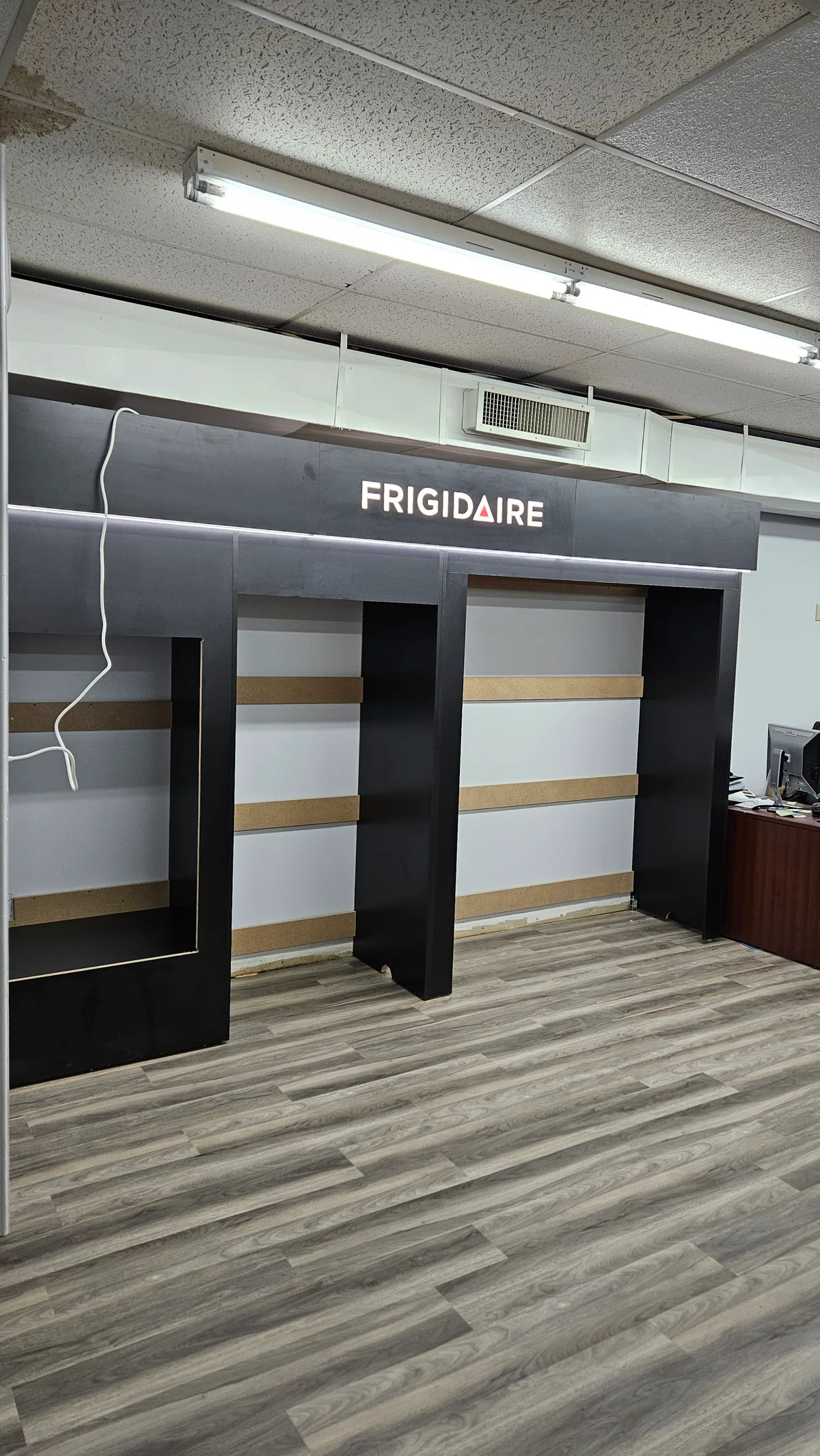 Black and white Frigidaire appliance display wall with integrated shelving